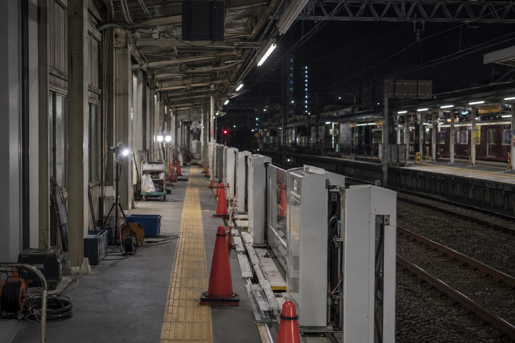 夜間、駅ホームでホームドアを設置している工事現場